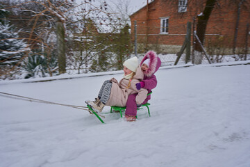 Winter fun, Happy children on sleds, two little girls happily sledding in winter