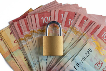 A padlock on Mexican peso banknotes. A concept of secure money with a padlock and stacks of bills.