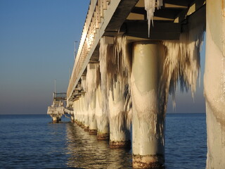 pier in the winter sea covered in icycles