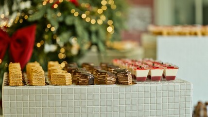 Festive holiday dessert buffet featuring layered cakes and individual parfaits with Christmas tree...
