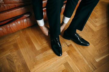 Man tying shoelaces on elegant black dress shoes