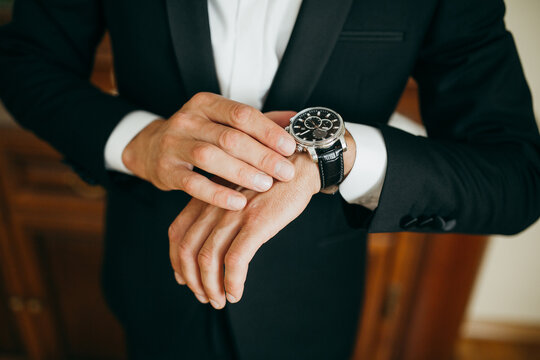 Man in classic tuxedo checking time on elegant watch