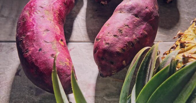 Overhead view, tour view of tropical fruit (sweet potato and pineapple) on a natural surface.