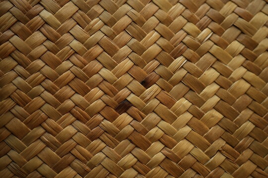 Natural raffia straw bag texture with a woven ornamental pattern. Close-up of handmade straw weaving in warm beige tones, ideal for fashion, eco design, summer accessories, backgrounds, and sustainabl