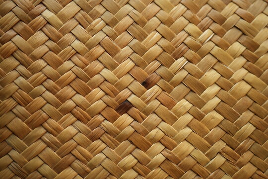 Natural raffia straw bag texture with a woven ornamental pattern. Close-up of handmade straw weaving in warm beige tones, ideal for fashion, eco design, summer accessories, backgrounds, and sustainabl