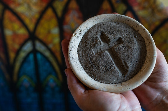 Hands with gray ash cross in church on stained glass window. background. Ash Wednesday