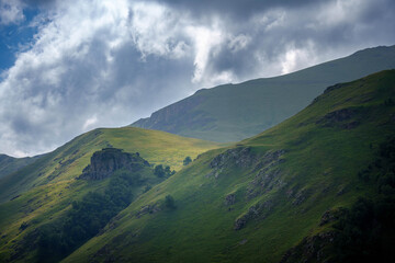 Expansive panoramic view of green mountain hills with dramatic cloudy sky.  N atural landscape captured in 7K high resolution on Sony A7 IV. Ideal for backgrounds or eco travel themes