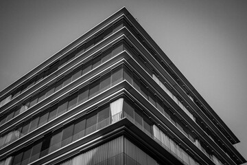 Black and white view of a modern building corner with glass balconies and geometric lines