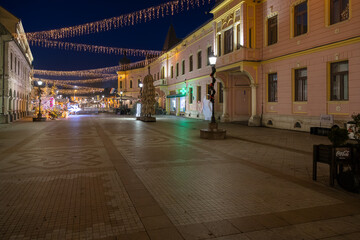 Festive European Street Scene With Christmas Lights, Historic Buildings, And Waterfront Walkway, Vinkovci, Croatia