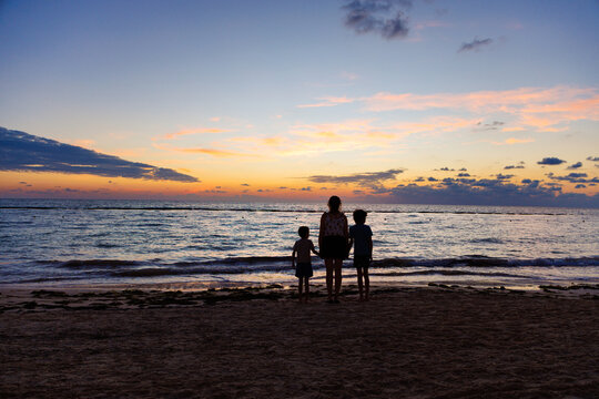 Woman and children contemplating the landscape at a beach in the Riviera Maya at sunrise