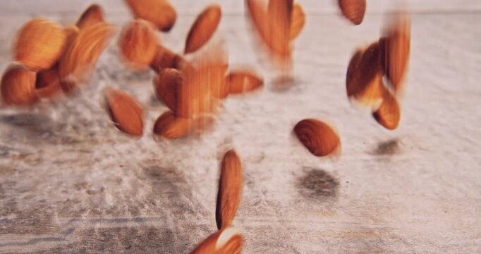 Front view of low speed falling of whole almonds on a natural surface.