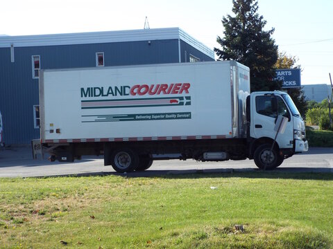 Ottawa, ON, Canada-July 8,2025: A "White Midland" Courier delivery truck is parked on a grassy shoulder on Michael Street.