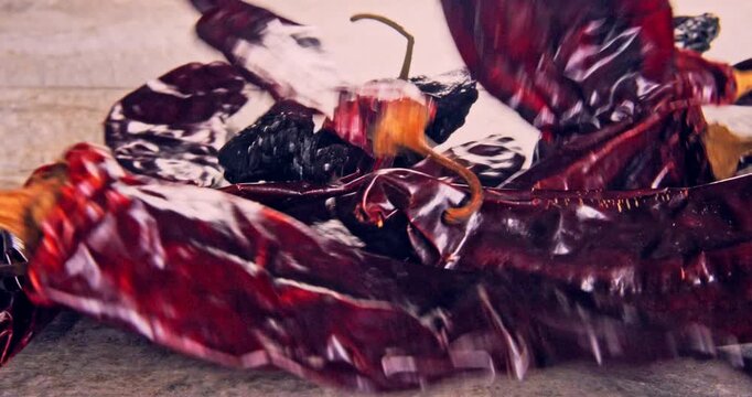 Front view of low speed fall of dried red chili peppers, on a natural surface.