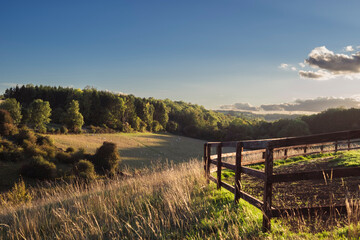 Rural sunset landscape in the Cotswolds with a wooden farm fence