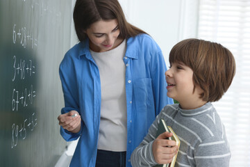 Teacher explaining mathematics at chalkboard and schoolboy in classroom