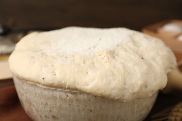 Fresh yeast dough in glass bowl on table, closeup