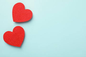 Love. Red decorative hearts on light blue background, flat lay. Space for text