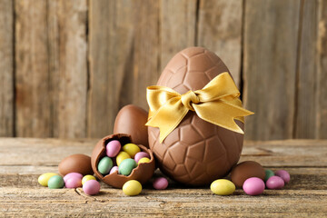 Tasty chocolate eggs with colorful candies on wooden table, closeup. Happy Easter