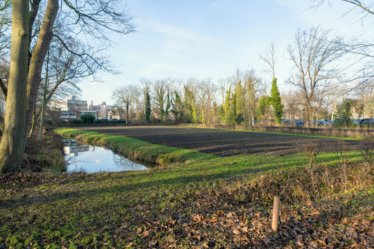  landscape with a small canal and a freshly plowed field under a clear sky