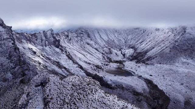 Dramatic aerial view of rocky mountain cirque with snw patches