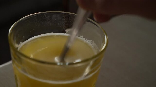 Powdered supplement mixed in a glass of water with a teaspoon