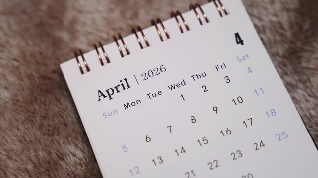 Close-up of April 2026 calendar page with finger pointing at date, concept of planning, scheduling and time management.