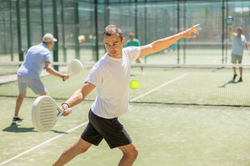 Obraz premium Active man with enthusiasm playing padel on the tennis court