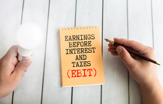 EBIT symbol. Concept words EBIT earnings before interest and taxes on white note on beautiful yellow background.