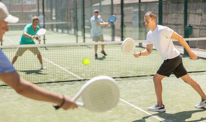 Four men practice playing padel on an outdoor tennis court © JackF