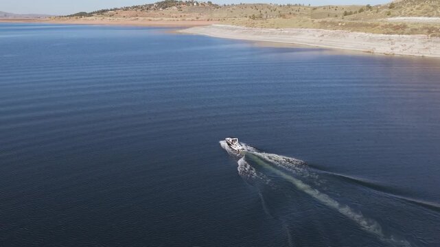 High aerial view of boat pulling wakeboarder across lake