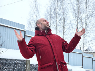An enthusiastic European man celebrates achieving a goal by raising his hands.