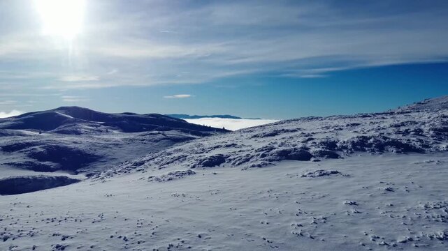 Snow covered mountain plateau with rolling hills and lue sky aerial winter landcape