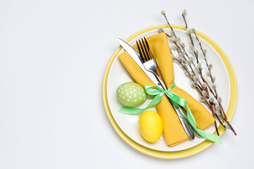 Easter celebration. Festive table setting with willow branches and painted eggs on white background, top view. Space for text