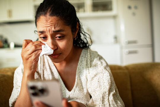 Sad woman crying at home while reading a smartphone message