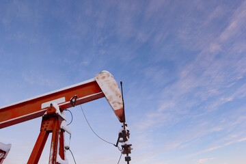 Obraz premium Oil pumpjack's horsehead against a soft pink winter sky at sunrise. Industrial energy production in rural Canada, cold season, oil and gas industry, prairie landscape.