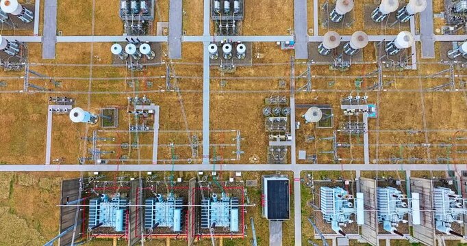 Aerial top down view of a high voltage electrical power substation with transformers and distribution equipment.