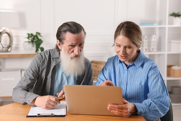 Notary consulting senior man about Last Will and Testament at wooden table in office