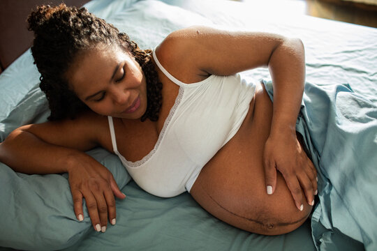 Pregnant woman resting on bed at home
