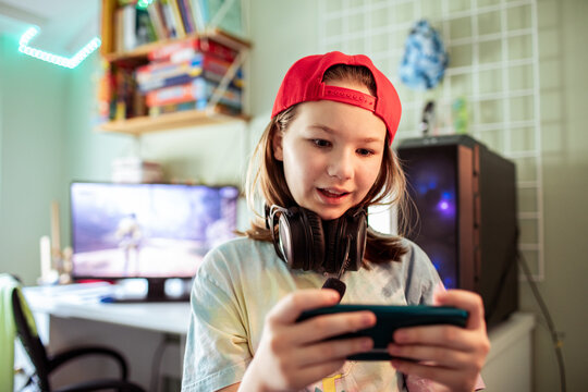 Tween girl gaming on smartphone at home desk