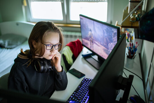Girl with headset playing computer game at home