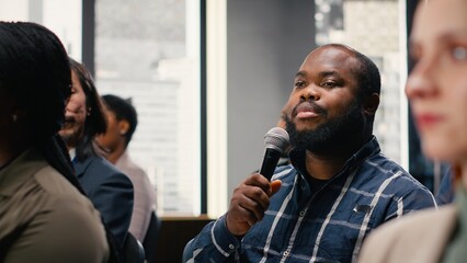 Participants engaging and interacting during presentation, asking questions on microphone. Corporate business meeting with panel discussion and executive speaker, international conference.