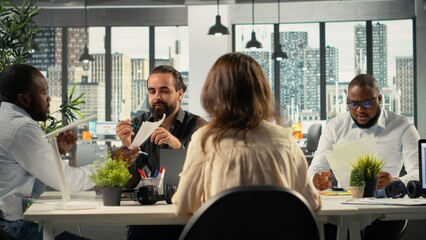 Diverse work team in multinational company analyzing metrics and projections. Staff collaborating on strategy planning and report sharing to support business targets.