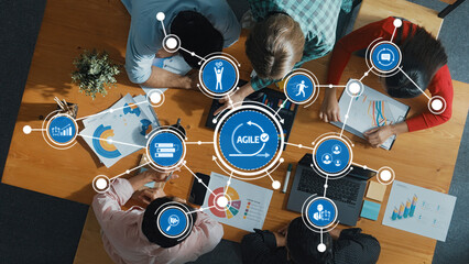 Aerial view of a collaborative team engaged in Agile project management, utilizing technology and visual data analysis in a bright and modern office environment. Amity