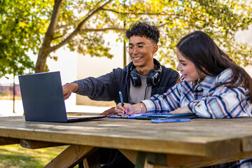 University students studying together outdoors with laptop and tablet