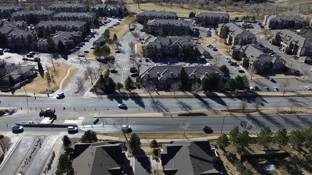East Loyola Drive apartment grid bordered by construction zone on South Buckley Road. Dark roofs, parked cars, and long shadows over treelined lots and active traffic lanes, Aurora, Colorado