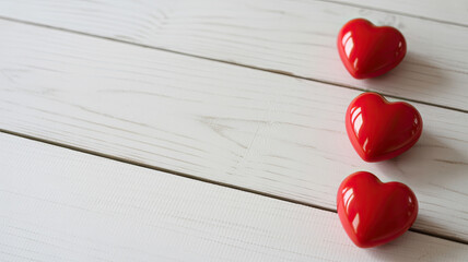 Three red hearts on a white wooden surface