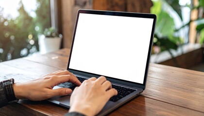 Close-up of user hands typing on modern laptop blank screen on wooden cafe table, mockup template for digital nomad and remote work concept.