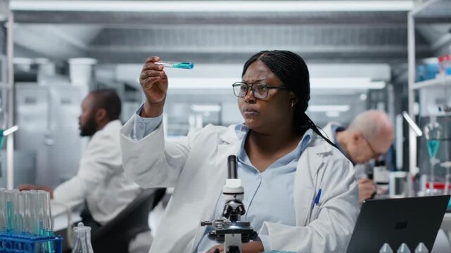 Lab materials scientist investigating blue liquid polymer properties in test tube container. Researcher testing new synthetic material durability and viscosity in lab, camera B