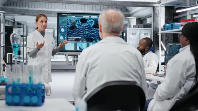 Biotechnology expert in lab presenting innovative DNA sequencing project to colleagues. Laboratory manager showing 3D biological model on screen to researchers during strategic briefing, camera B