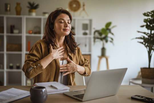 Woman wearing headset meditating during mindful deep breathing exercise